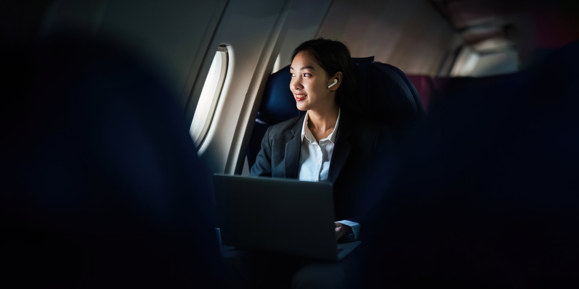Successful Asian business woman working in airplane cabin during flight