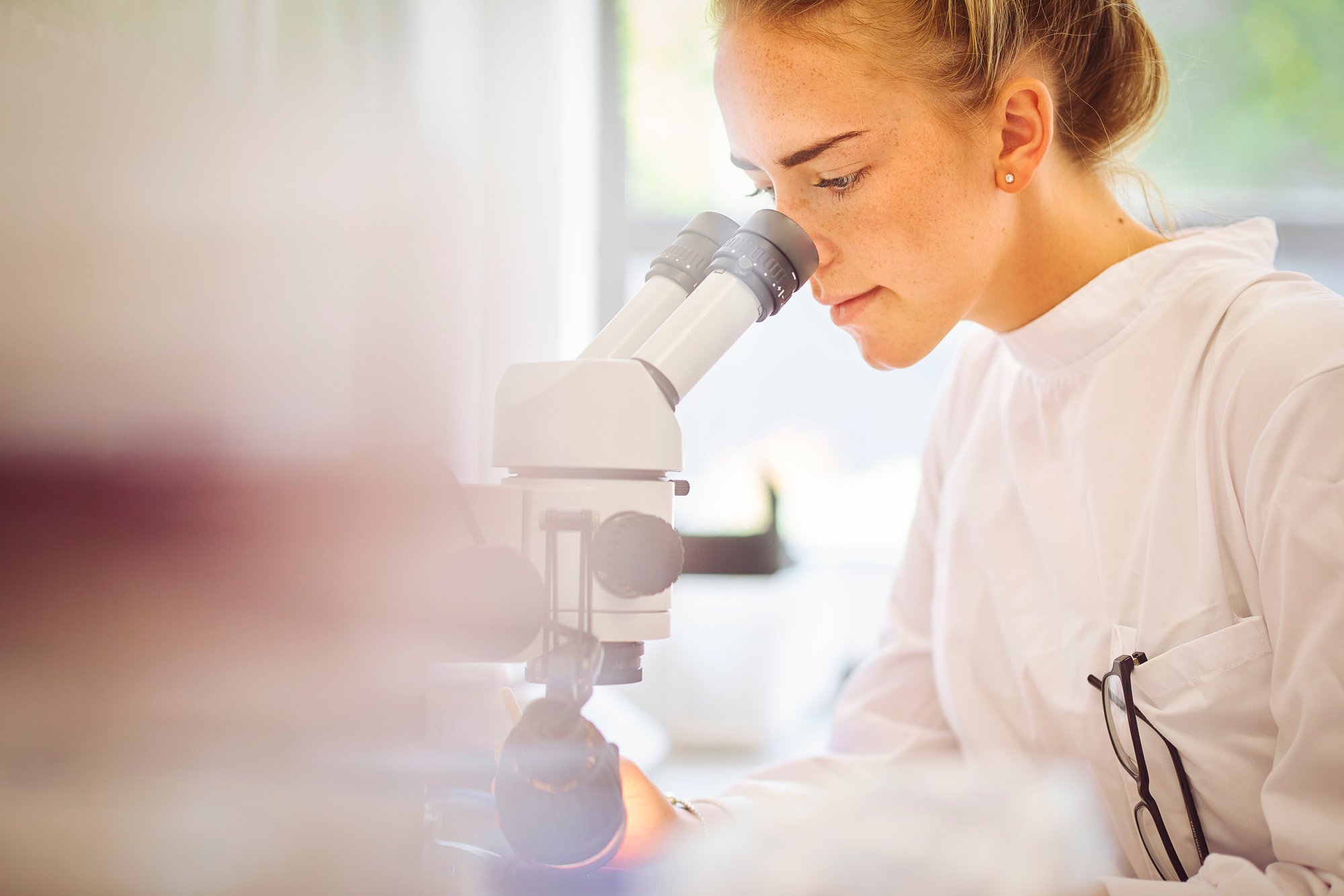 Young female pharmaceutical worker with microscope Young female pharmaceutical worker with microscope